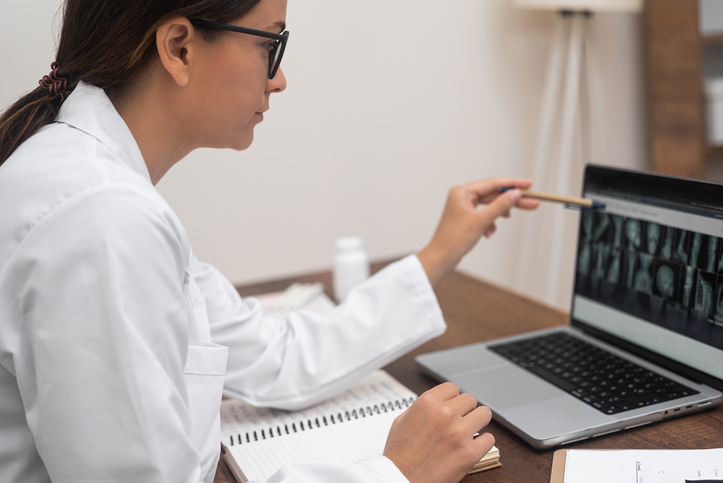 A doctor pointing at X-ray images on a laptop screen, demonstrating the use of advanced PACS software.