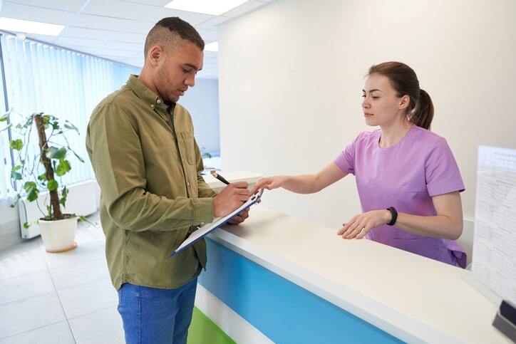 Patient at the front desk providing personal information for RIS system entry.